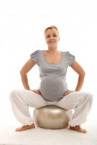 Confident pregnant woman sitting on exercise ball